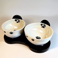 A set of ceramic food bowls on stands  There are 2 bowls included: 1 with a paw pattern, 2 with a fish pattern. There is an individual black stand for each of the bowls.